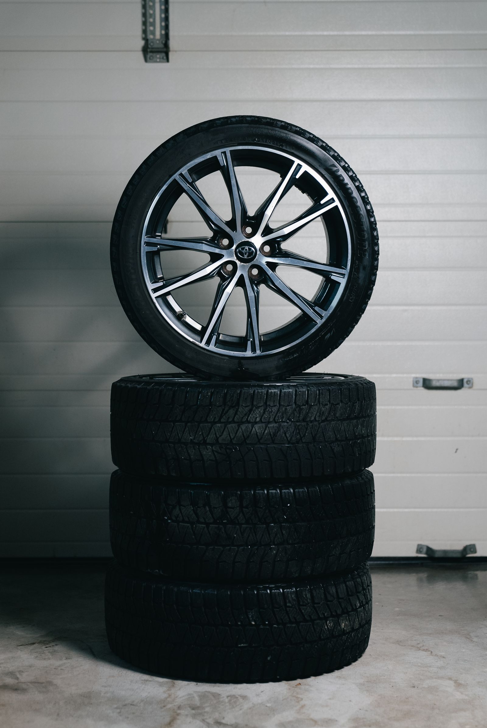 Stack of new tires with a wheel on top in a garage